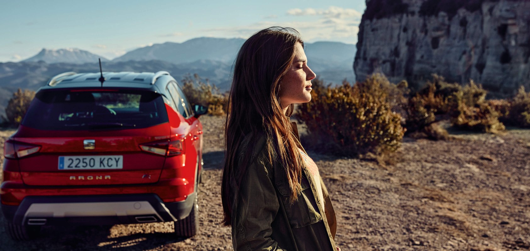 SEAT servizi auto nuove – vista posteriore di un SUV SEAT Arona crossover parcheggiato in un deserto con la vista di profilo di una donna