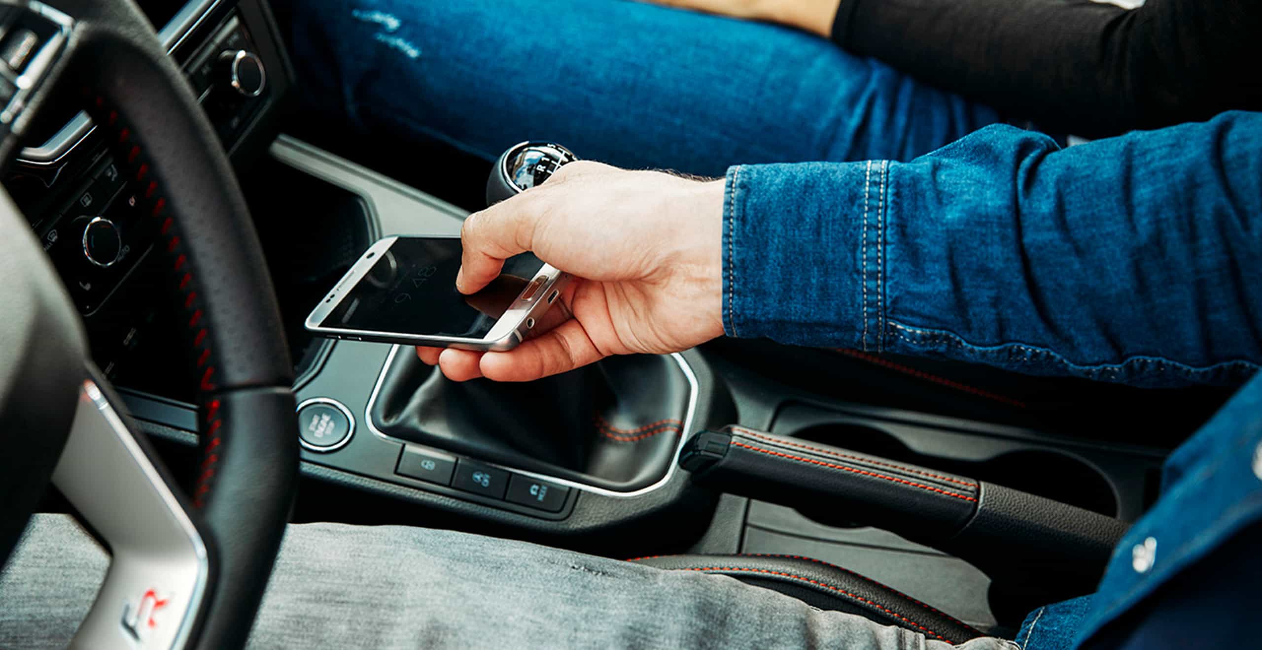 Mężczyzna odkłada telefon do schowka z wbudowaną ładowarką bezprzewodową w nowym ekonomicznym miejskim samochodzie SEAT Ibiza