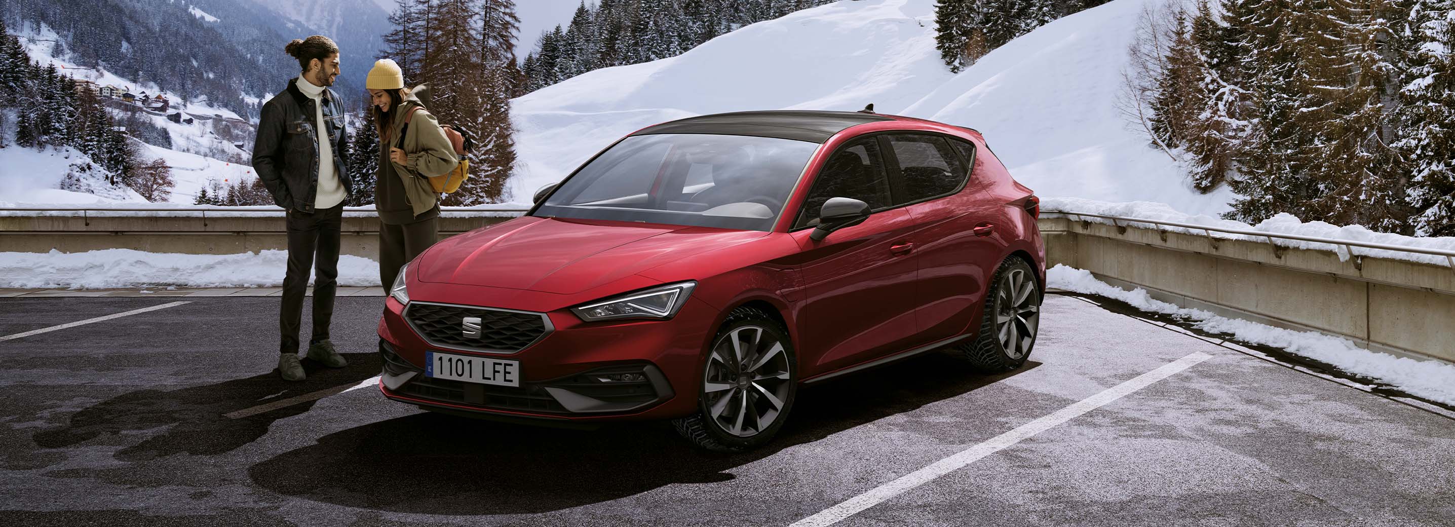 Ein Paar unterhält sich im SEAT Leon in Desire Red