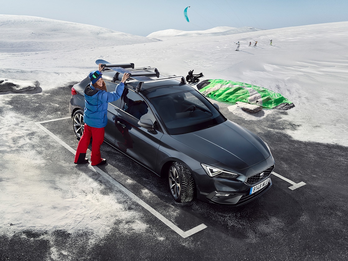 Rückansicht des SEAT Leon in Desire Red mit einem Paar, das den Berg bewundert