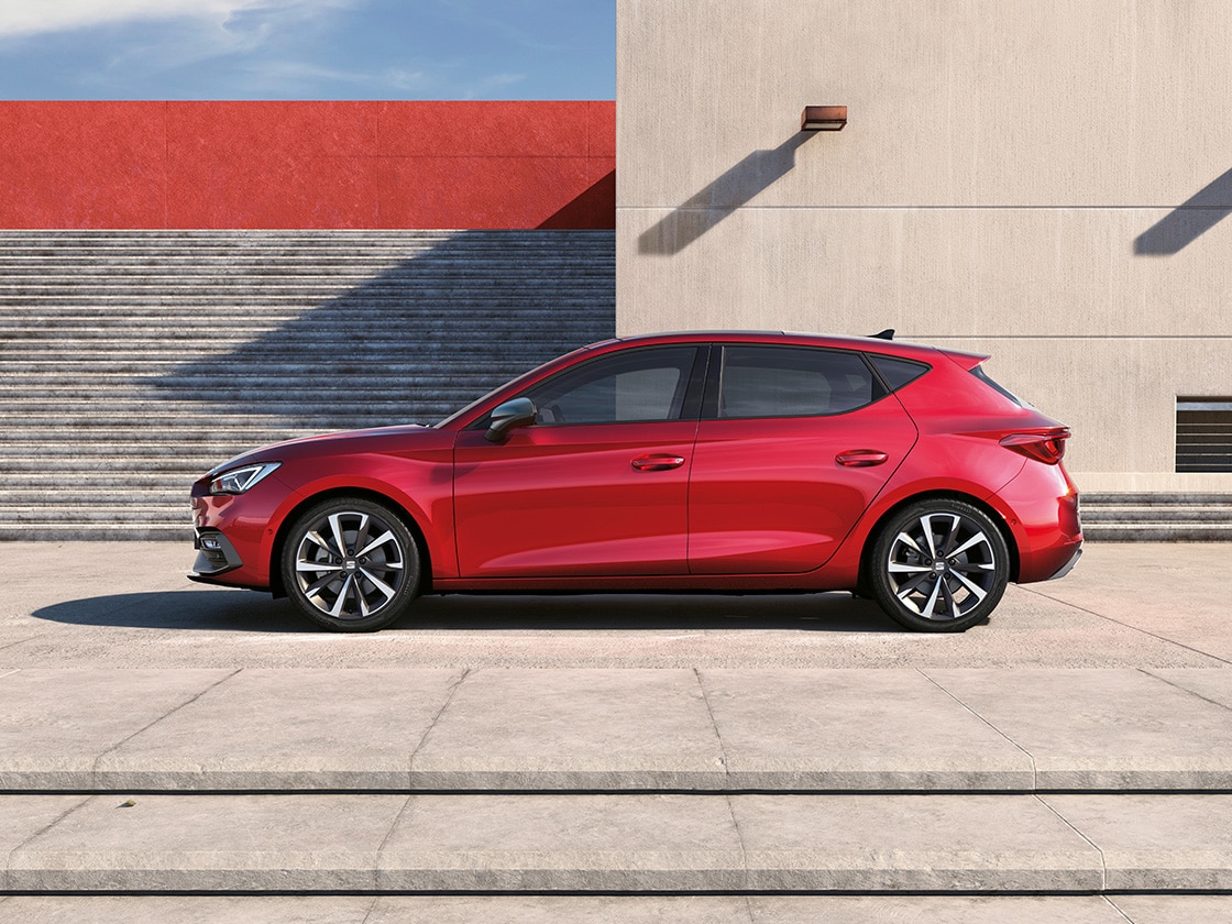 Ein Paar unterhält sich neben einem SEAT Leon in Desire Red