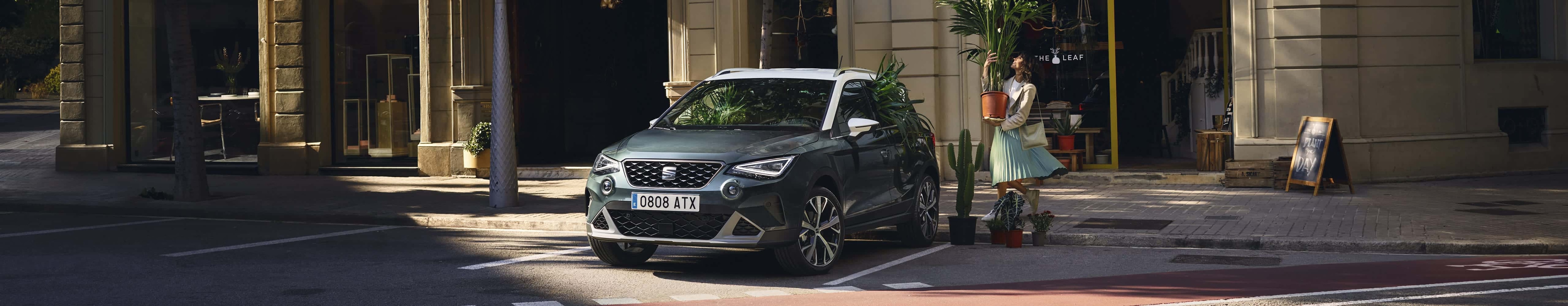 Une femme qui marche en direction d’une SEAT Arona couleur dark camouflage