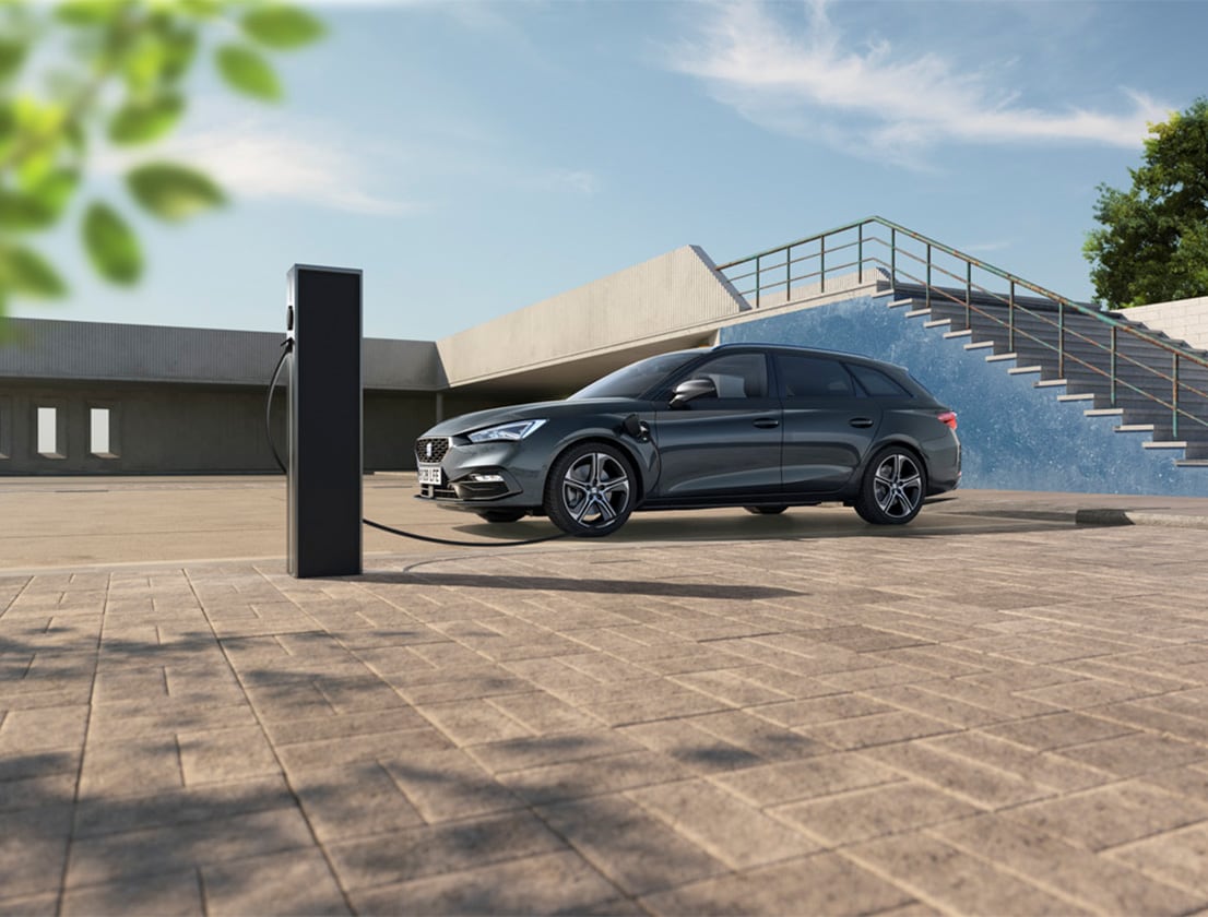 un uomo si allontana dalla seat leon e-hybrid in desire red con in mano il suo smartphone