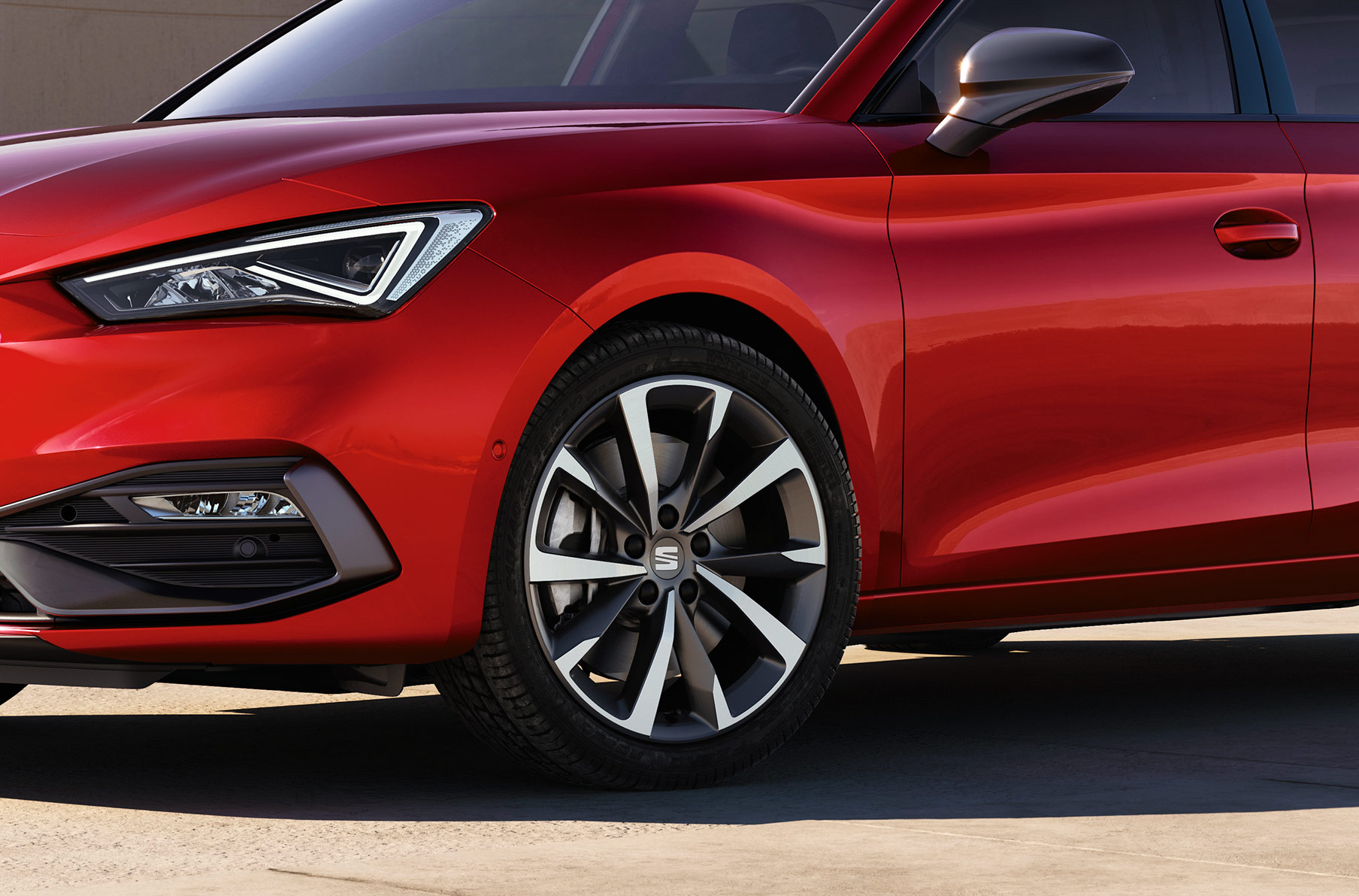 uomo in piedi accanto a una seat leon in desire red con cerchi in lega leggera performance