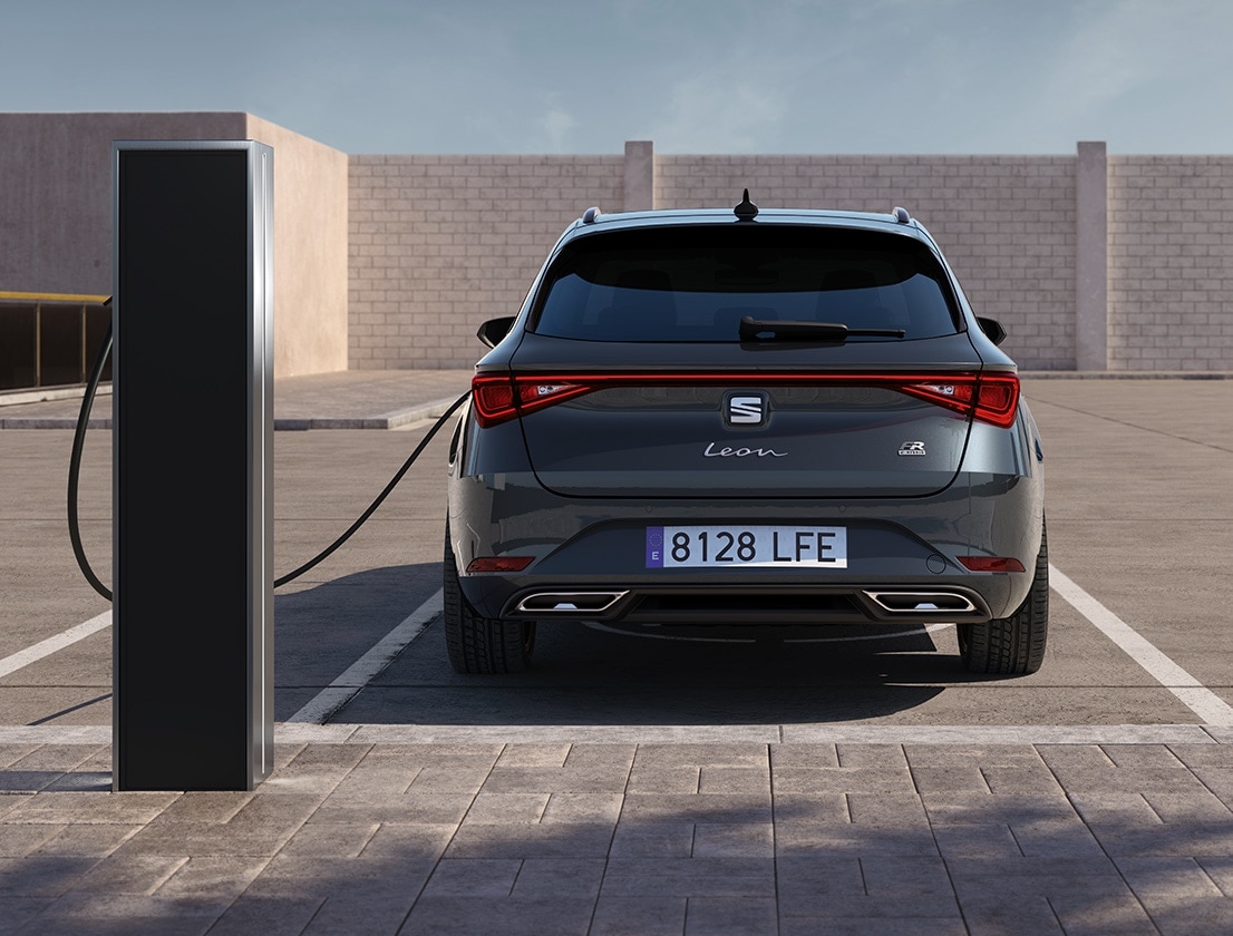 SEAT leon sportstourer e-hybrid w kolorze magnetic tech podłączony do ładowarki na parkingu