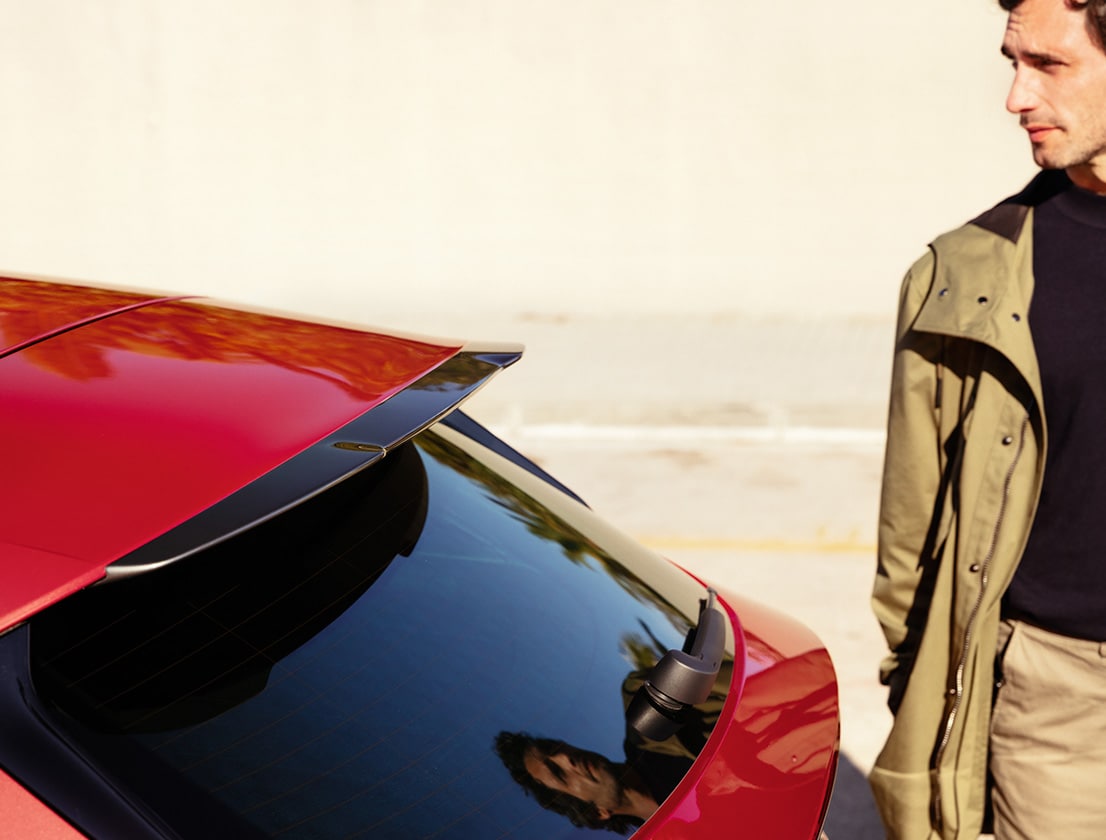 un uomo guarda lo spoiler sul tetto di una seat leon in cosmo grey