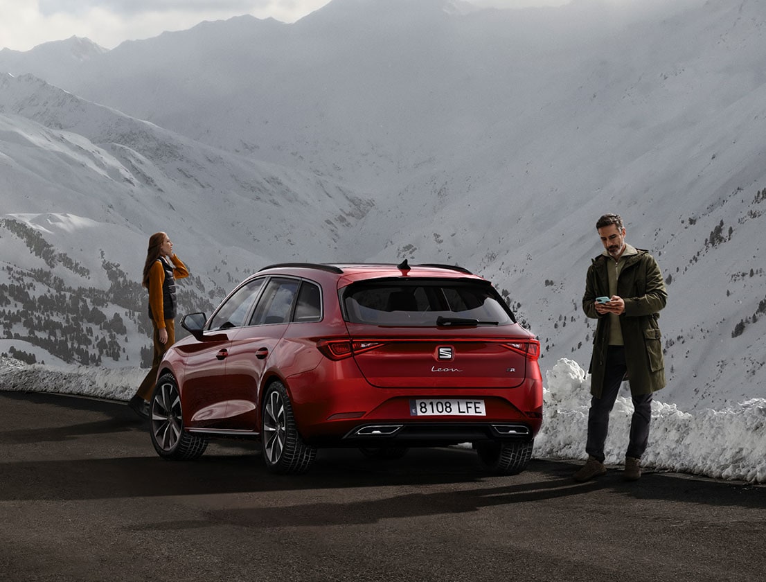 Rückansicht des SEAT Leon in Desire Red mit einem Paar, das den Berg bewundert