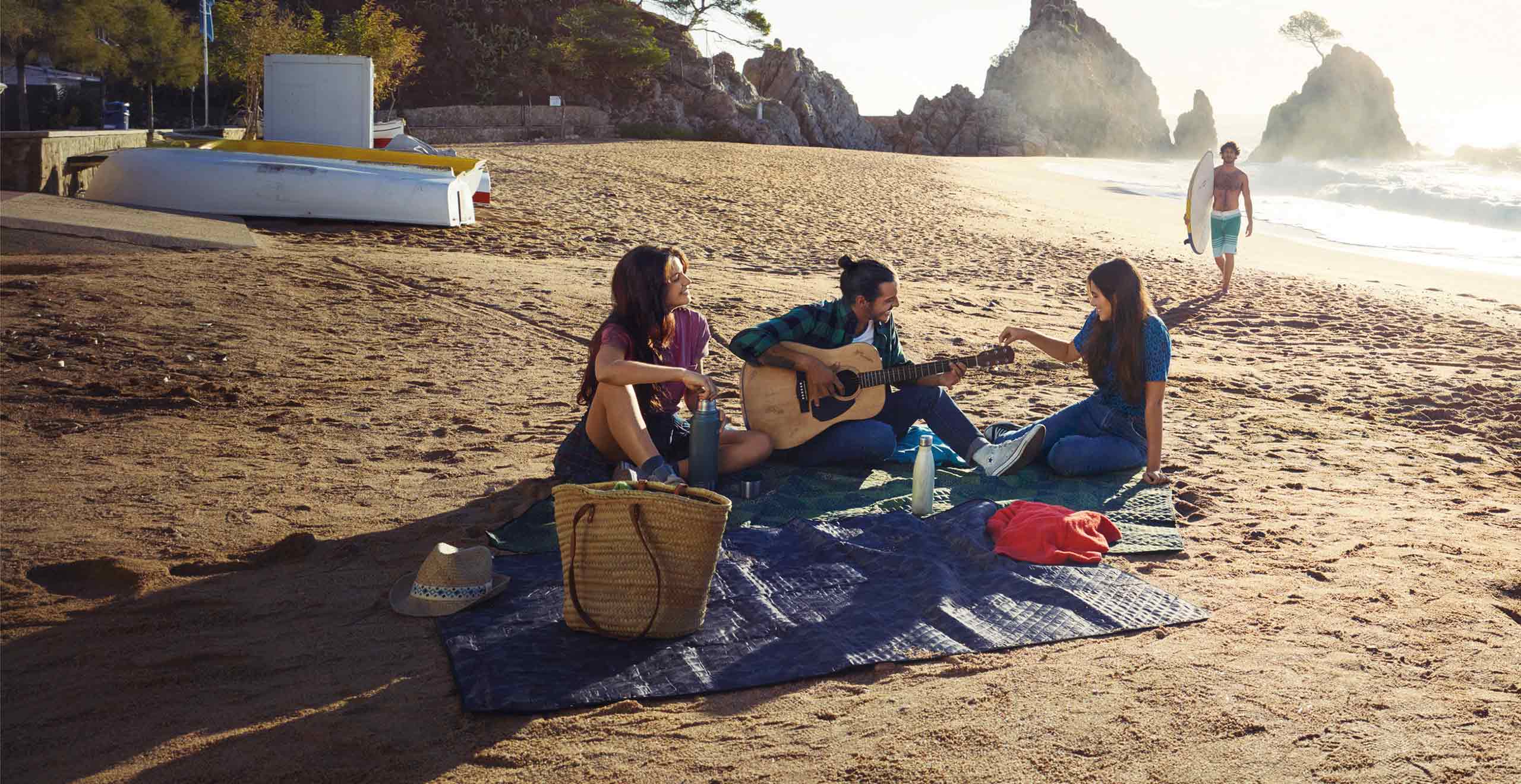 Des amis assis sur une plage à côté d’une SEAT Ibiza 