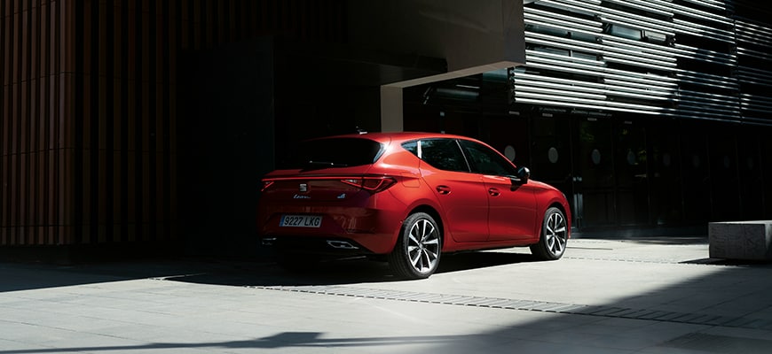 Sedile elettrico ibrido leggero leon sportstourer in rosso parcheggiato nell’ombra da un edificio