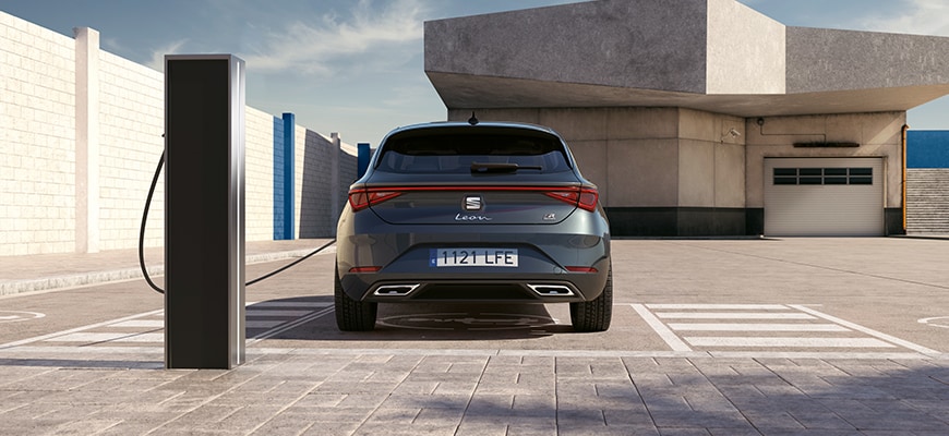 seat leon phev presso una stazione di ricarica, che illustra una guida completa alle auto ibride per conducenti eco-consapevoli