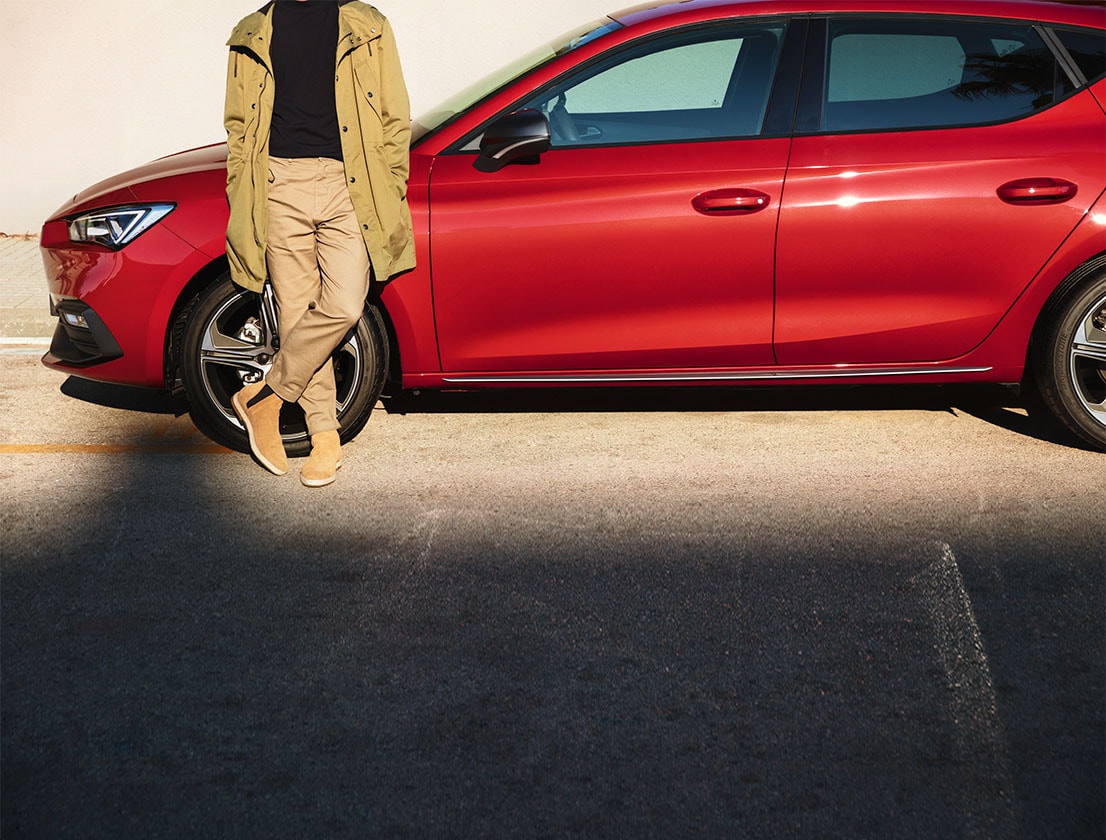 uomo in piedi accanto a una seat leon sportstourer in desire red 