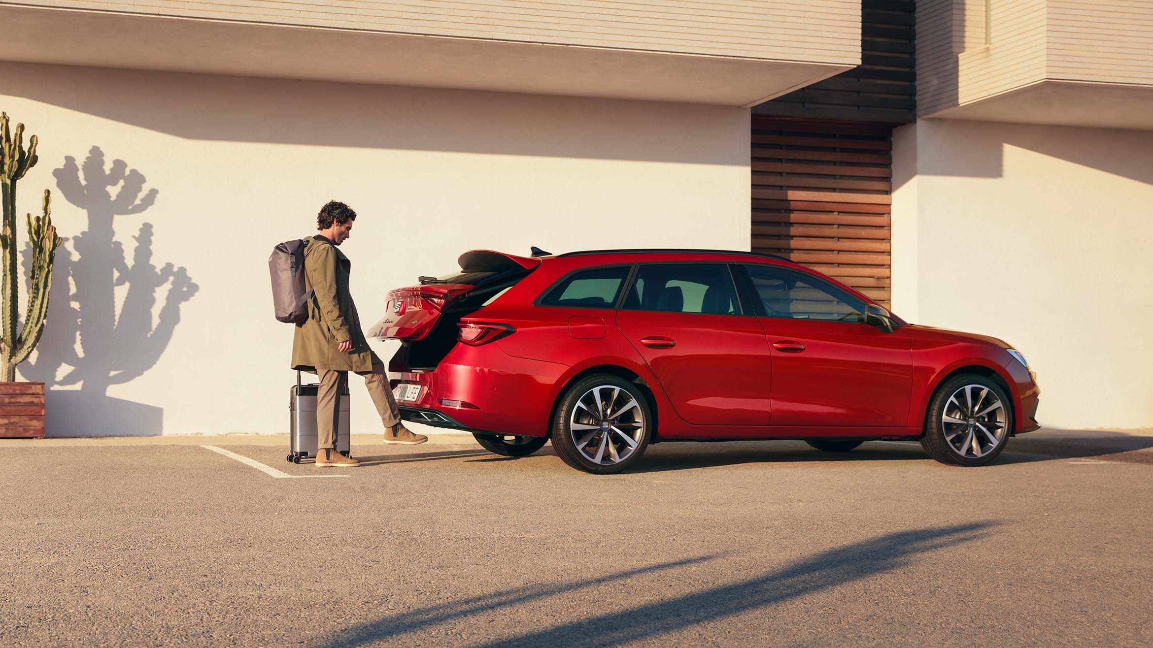 un uomo apre il bagagliaio di una seat leon in desire red 