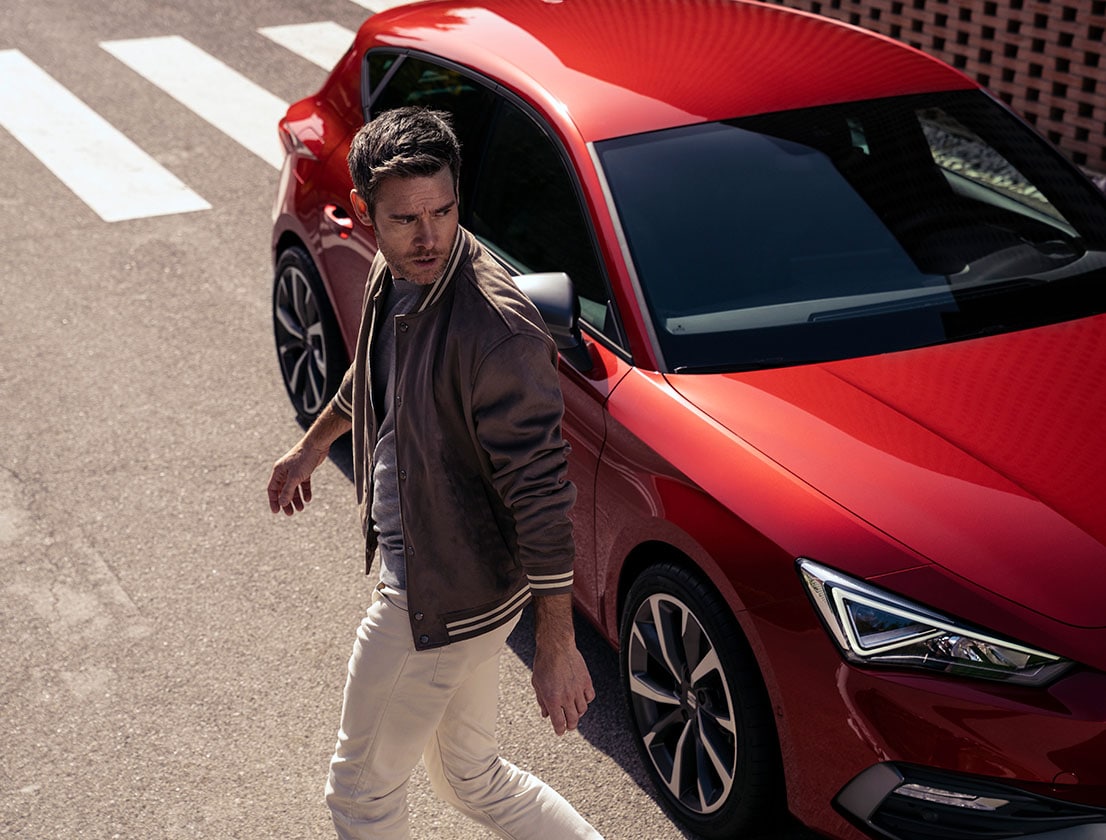 un uomo si allontana dalla seat leon in desire red con cerchi in lega leggera