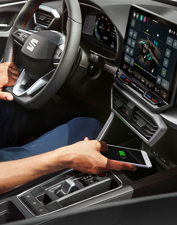 un uomo ricarica il suo smartphone con il caricatore wireless della seat leon
