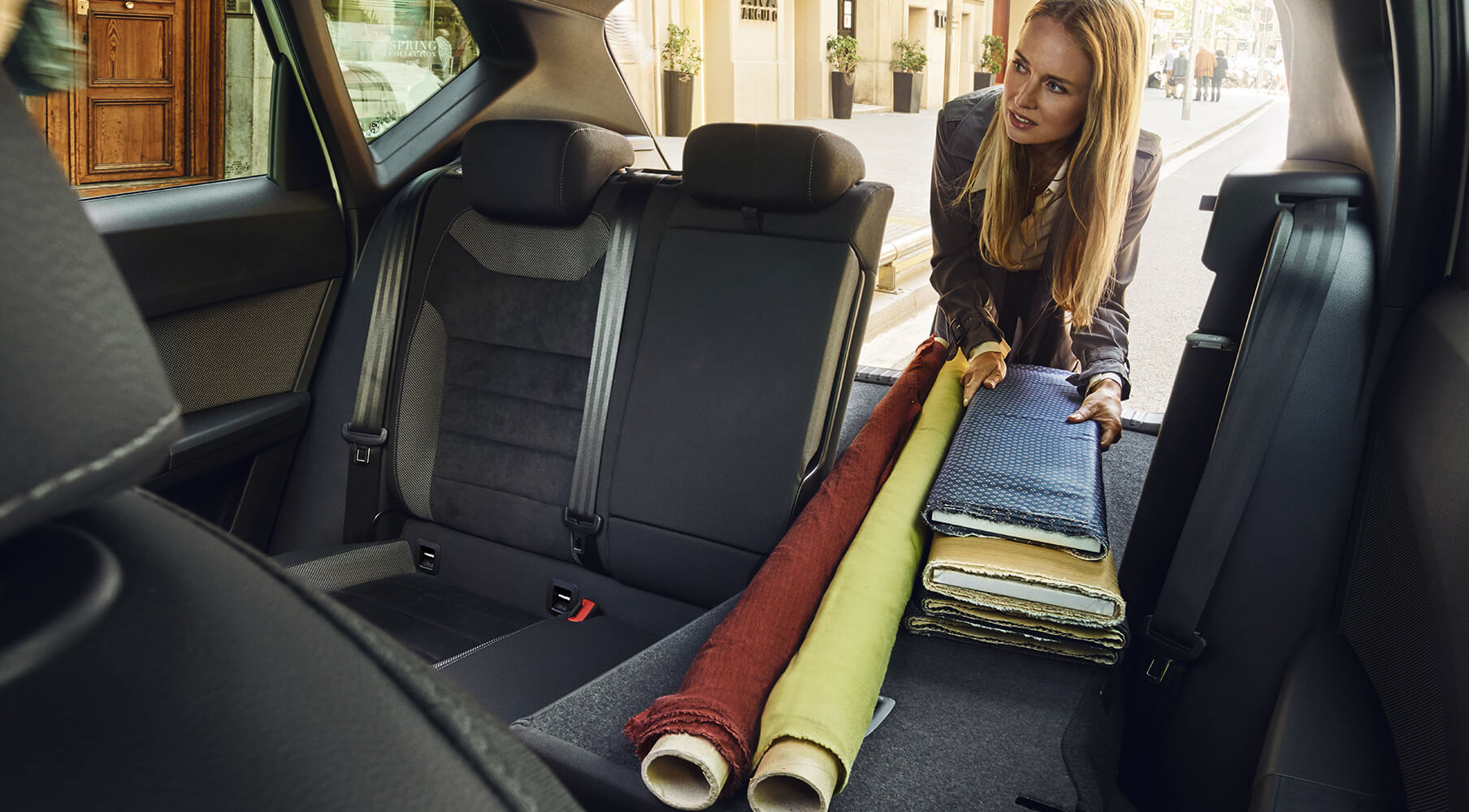 SEAT servizi auto nuove e manutenzione – Una donna sistema degli oggetti nei sedili posteriori di un’auto con il sedile abbassato per avere più spazio
