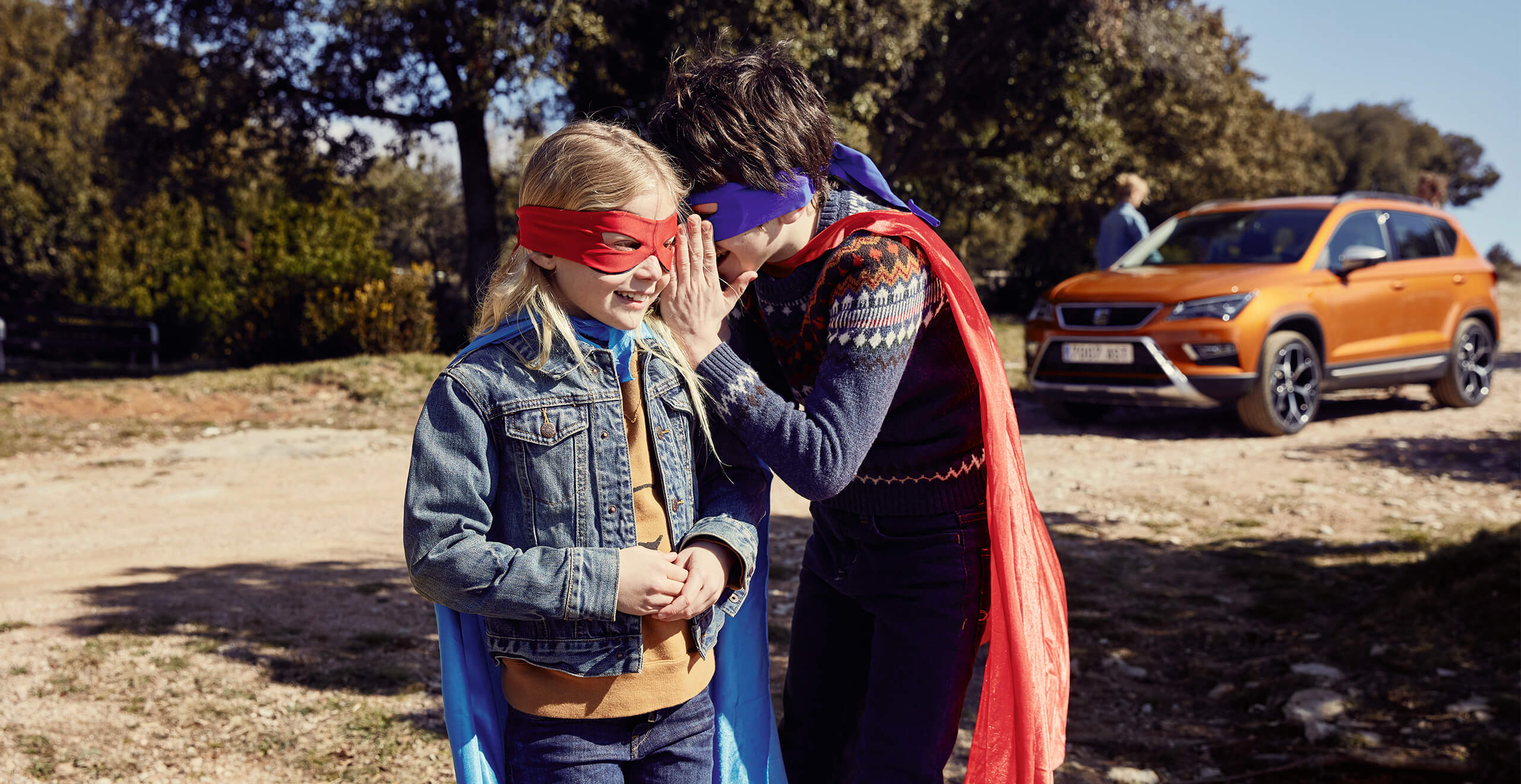 SEAT Service und Wartung - Besitzer –  zwei Kinder, die Superman-Kostüme anhaben und vor einem SEAT Ateca SUV spielen