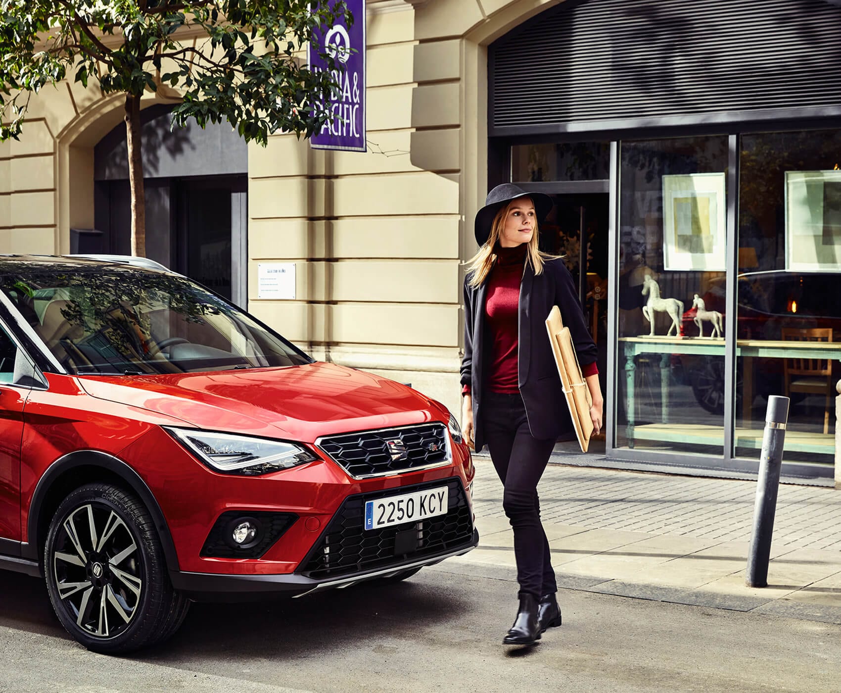 SEAT servizi auto nuove manutenzione controlli revisione – una donna cammina davanti a un SUV crossover SEAT Arona rosso