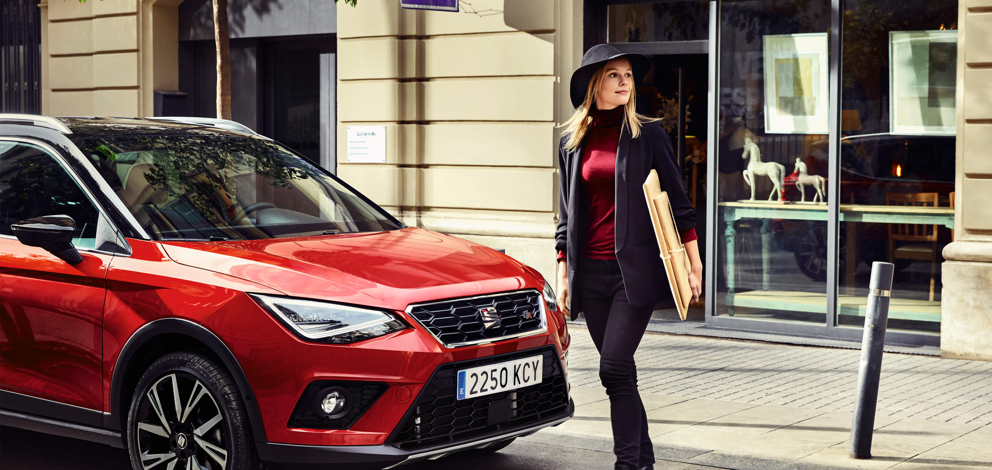 SEAT neuer Service und Wartung – MFK-Prüfung – Frau geht vor einem SEAT Arona Crossover SUV in Red
