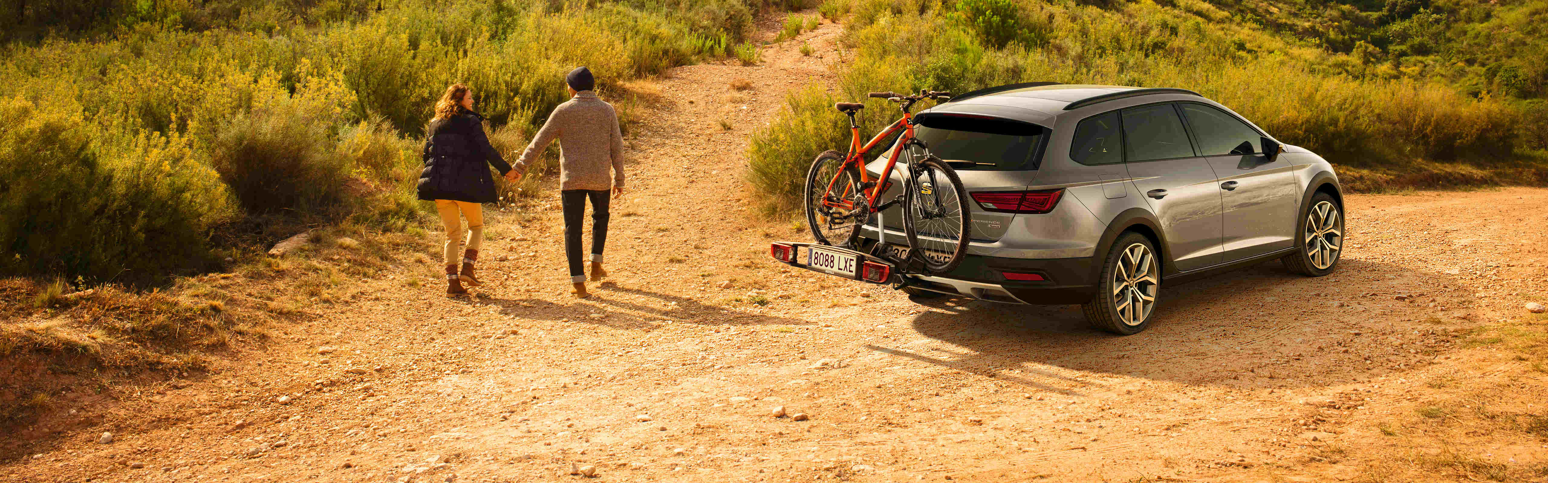 SEAT neuer Service und Wartung – Landschaftsaufnahme eines SEAT Leon mit Fahrradträger an der Seite eines Hügels