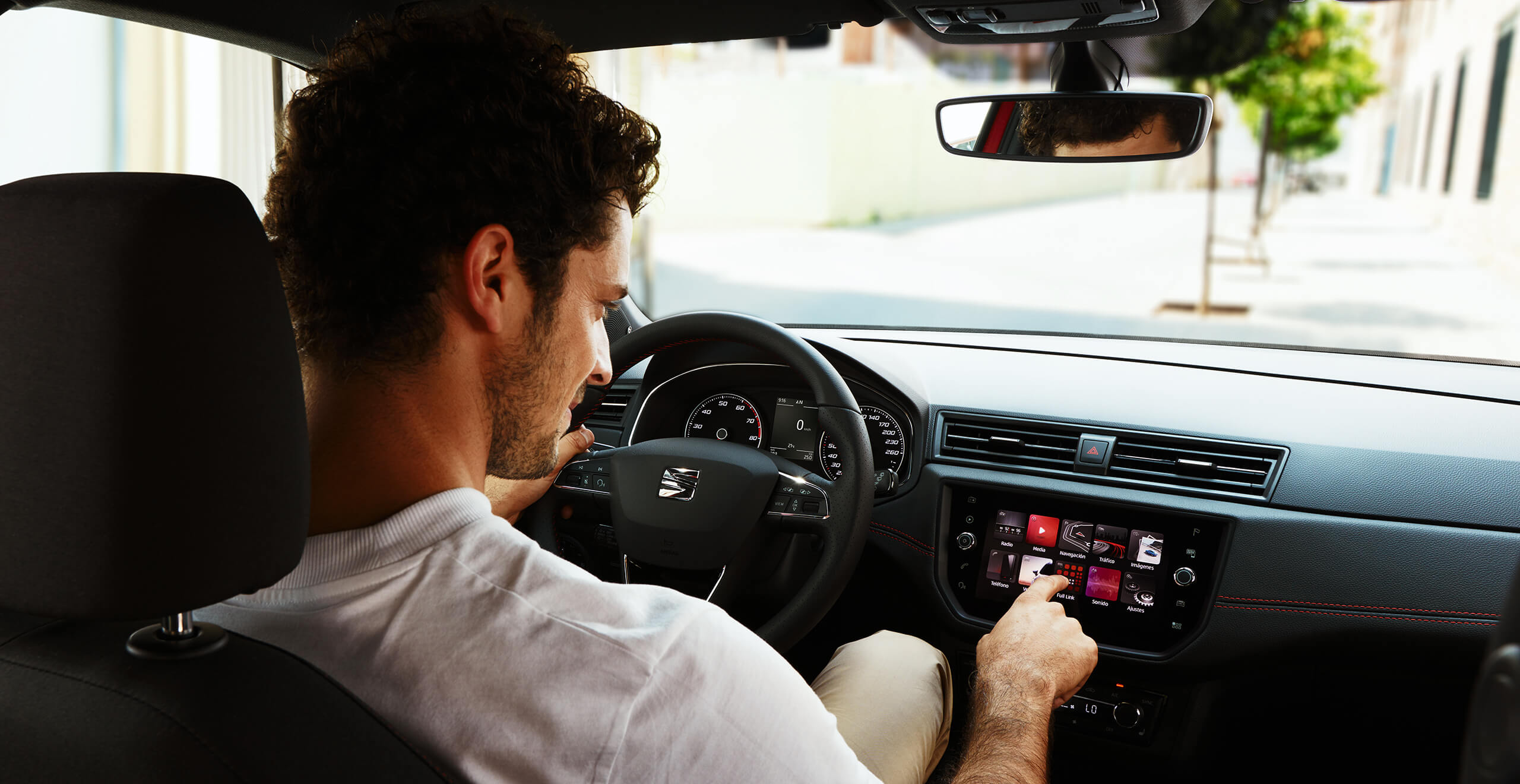 SEAT neuer Service und Wartung – Interieur-Ansicht eines männlichen Fahrers von hinten, der einen Knopf auf dem Cockpit eines neuen SEAT drückt